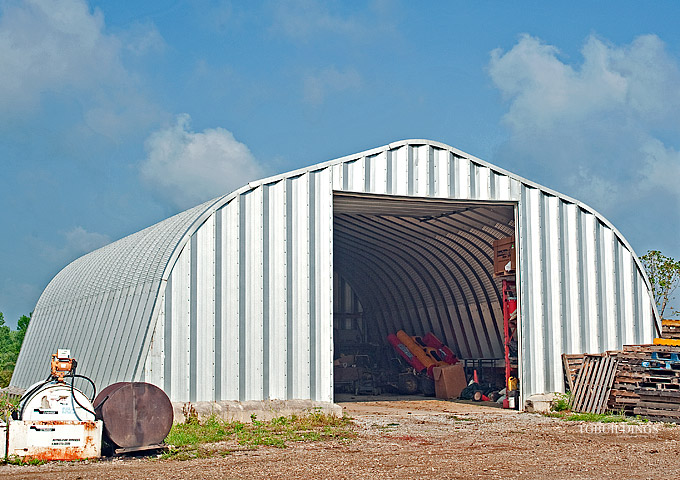 Prefabrykowane samonośne hale łukowe TG - samonośna hala łukowa typu A z bramą systemową, zastosowana jako magazyn, garaż na maszyny.